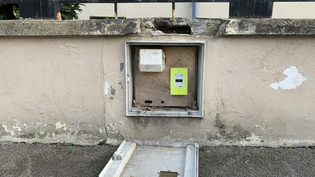 Compteur électrique Linky vert installé dans un coffret en façade d'une maison